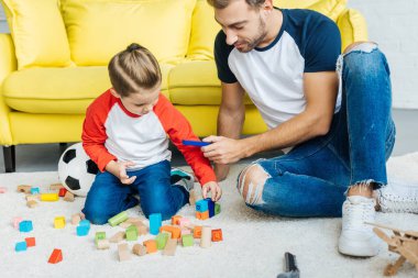 Baba ve sevimli küçük oğul ahşap bloklar ile birlikte evde oynamak