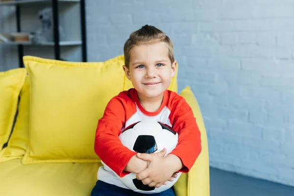 Retrato Menino Sorridente Com Bola Futebol Mãos Descansando Sofá Amarelo — Fotografia de Stock