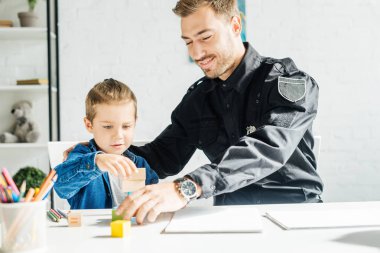 Polis üniforması mutlu genç baba ve oğul birlikte evde oynamak