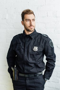 yakışıklı genç polis memuru önünde beyaz tuğla duvar portresi