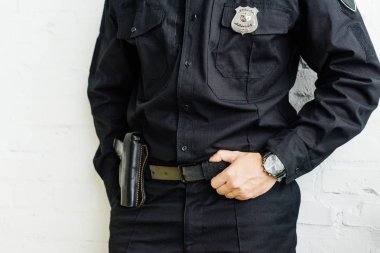 Polisin beyaz tuğla duvarın önünde, ayakta kırpılmış atış