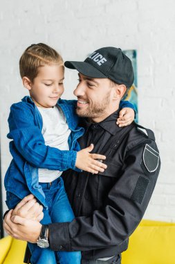 küçük oğlu taşıyan polis üniformalı yakışıklı genç baba