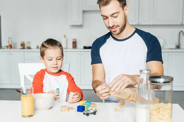 父亲和儿子玩木积木和玩具飞机早餐后在厨房 — 免费的图库照片