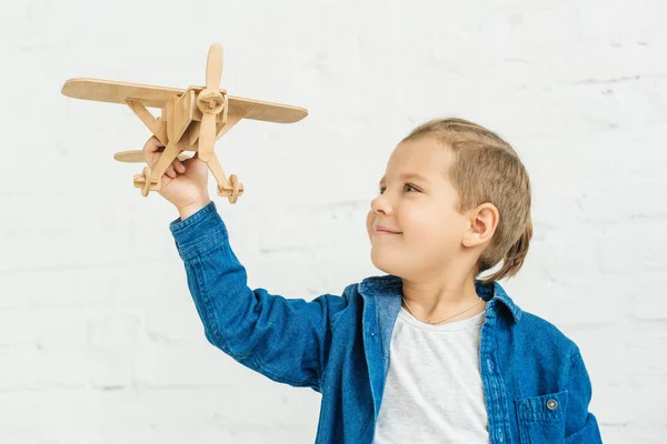 Criança Feliz Brincando Com Avião Brinquedo Madeira Frente Parede Tijolo — Fotografia de Stock
