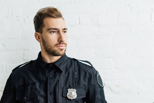 portrait of thoughtful young policeman in front of white brick wall