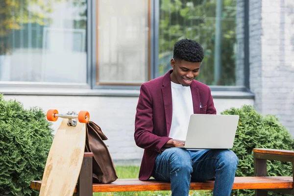 微笑年轻的非洲裔美国学生使用笔记本电脑在街道上 — 图库照片