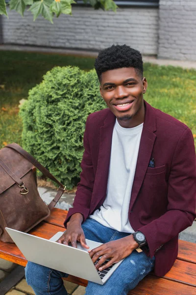Sonriente Joven Afroamericano Estudiante Utilizando Portátil Calle Mirando Cámara — Foto de Stock