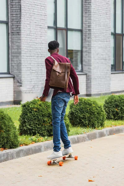 Widok Tyłu Studenta Plecaka Notebooki Jeżdżenie Deskorolce Ulicy — Zdjęcie stockowe