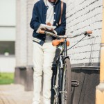 Selective focus of african american freelancer writing documents and standing at bicycle on street