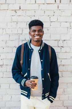 Beyaz tuğla duvara yakın gitmek için kahve holding neşeli Afrikalı-Amerikalı adam 