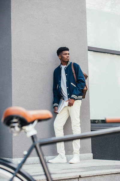 selective focus of handsome african american freelancer with documents and bicycle 