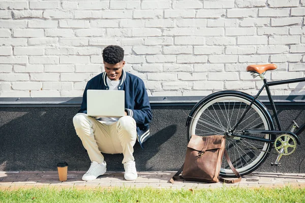 Teletrabajador Afroamericano Utilizando Portátil Cerca Bicicleta Con Mochila Cuero Café — Foto de stock gratuita