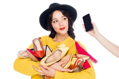 beautiful stylish woman holding heap of shoes while talking on smartphone isolated on white 
