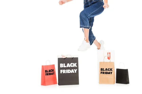 女孩跳近购物袋与黑色星期五销售标志查出的白色的短视图 — 图库照片
