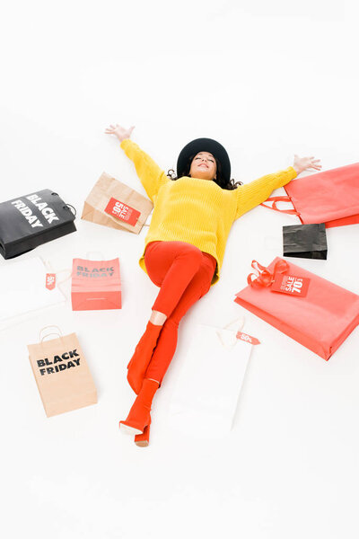 модная привлекательная девушка лежит рядом с сумками для покупок на черной пятничной распродаже, изолированные на белом
