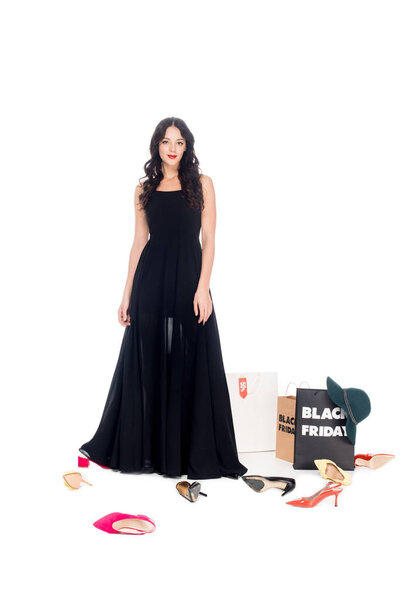 attractive woman in black dress posing with female shoes and shopping bags around isolated on white