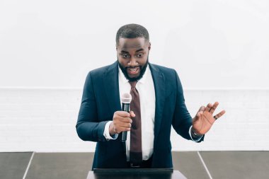 Afro-Amerikan hoparlör seminer konferans salonunda sırasında mikrofona konuşurken gülümseyen, yüksek açılı görünüş