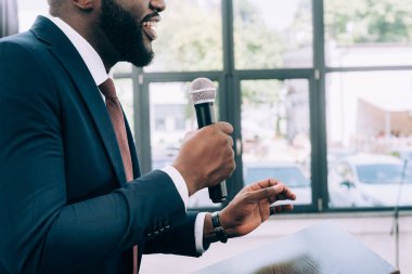 Afro-Amerikan hoparlör seminer konferans salonunda sırasında mikrofona konuşurken gülümseyen bir görüntü kırpılmış