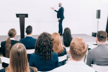 selective focus of african american lecturer talking to audience during seminar in conference hall clipart