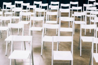 Konferans salonunda düzenlenen boş beyaz sandalye görünümünü kapat