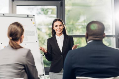 kadın iş öğretim görevlisi konferans salonunda çok kültürlü meslektaşları ile seminer sırasında malzeme sunmak