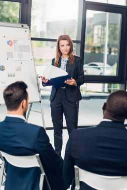 kadın iş öğretim görevlisi konferans salonunda çok kültürlü meslektaşları ile seminer sırasında malzeme sunmak