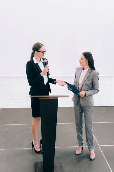 высокий угол обзора привлекательного лектора глядя на улыбающегося ассистента во время семинара в конференц-зале
