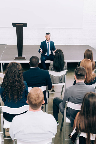 спикер, сидящий на сцене во время семинара в конференц-зале
