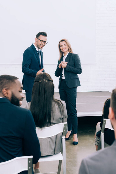 улыбающиеся коллеги во время семинара в конференц-зале
