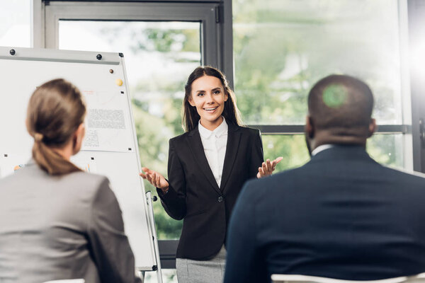 female business lecturer presenting material during seminar with multicultural colleagues in conference hall
