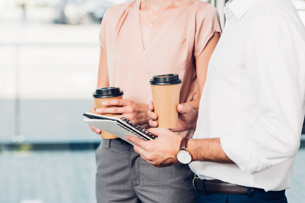 partial view of business colleagues with coffee to go in conference hall