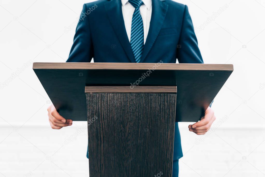 cropped image of lecturer standing at podium tribune during seminar in conference hall