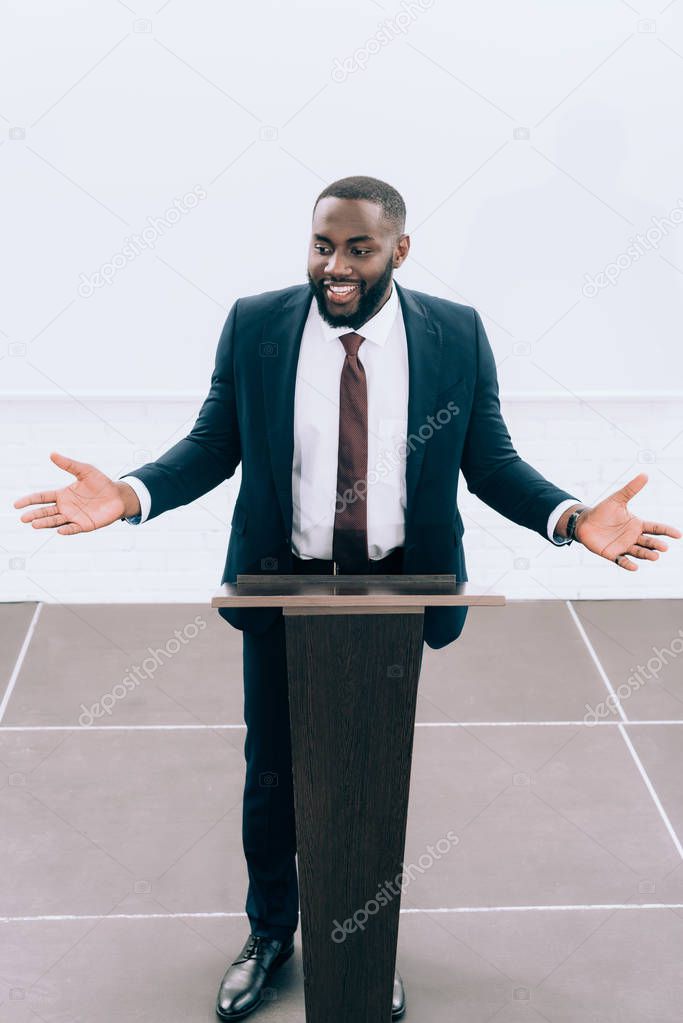 high angle view of smiling african american lecturer gesturing at podium tribune during seminar in conference hall