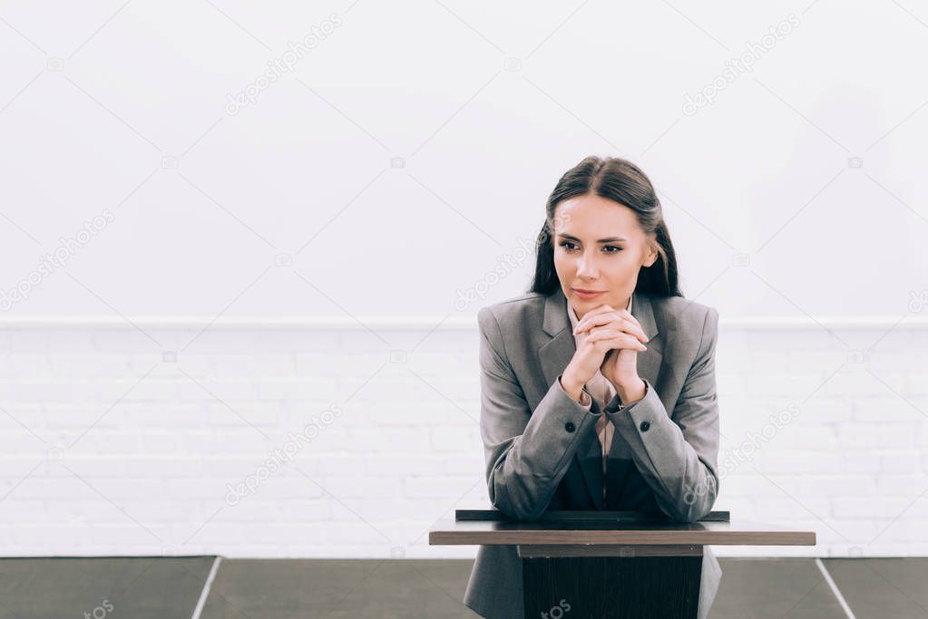 attractive lecturer leaning on podium tribune during seminar in conference hall