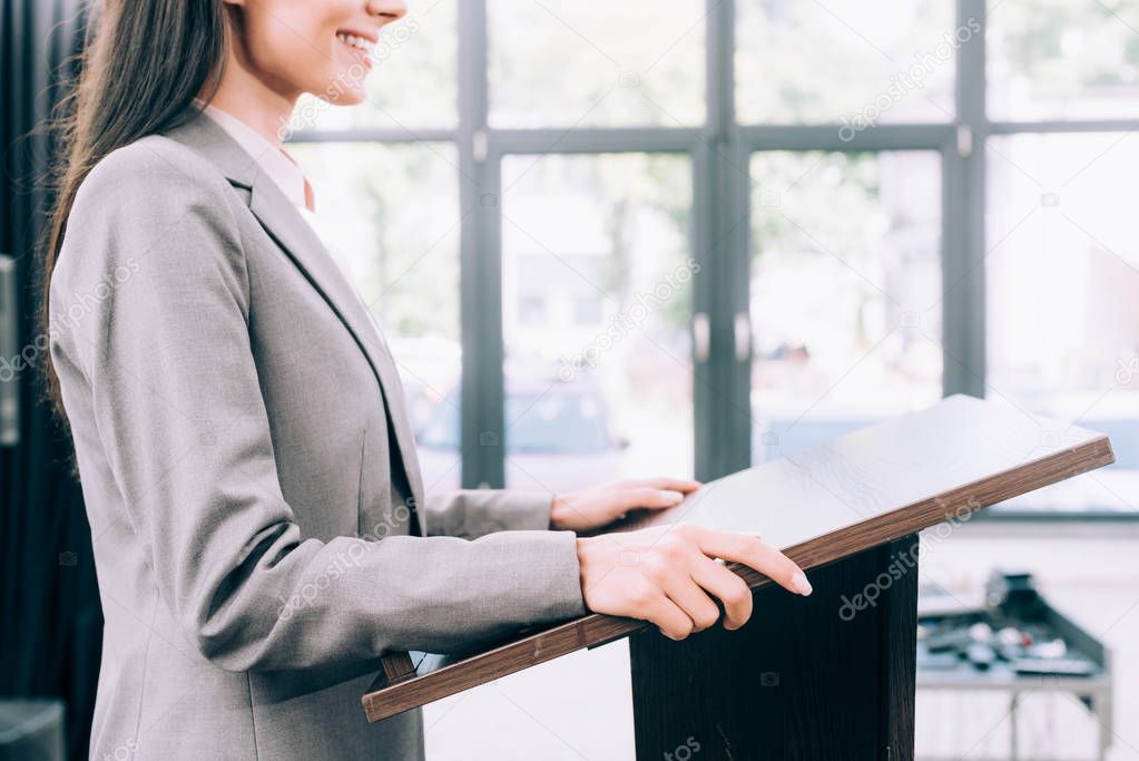 cropped image of smiling lecturer standing at podium tribune during seminar in conference hall