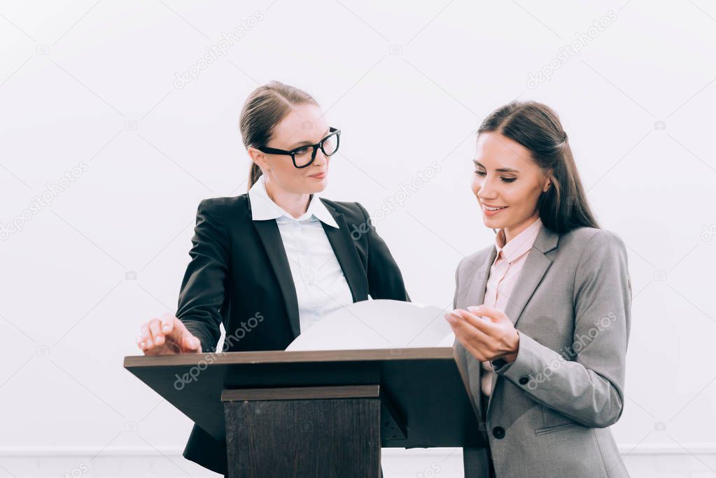 beautiful assistant showing documents to attractive speaker during seminar in conference hall