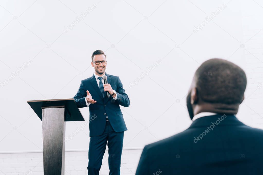 smiling caucasian lecturer talking to african american listener during seminar in conference hall