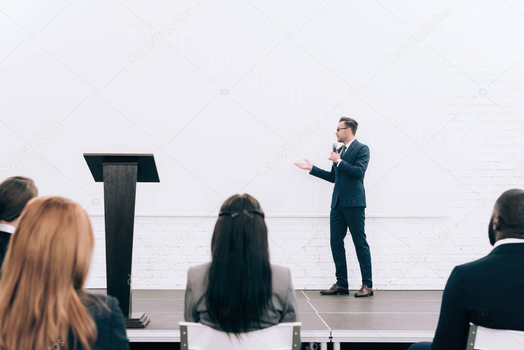 handsome speaker talking during seminar in conference hall and pointing on screen