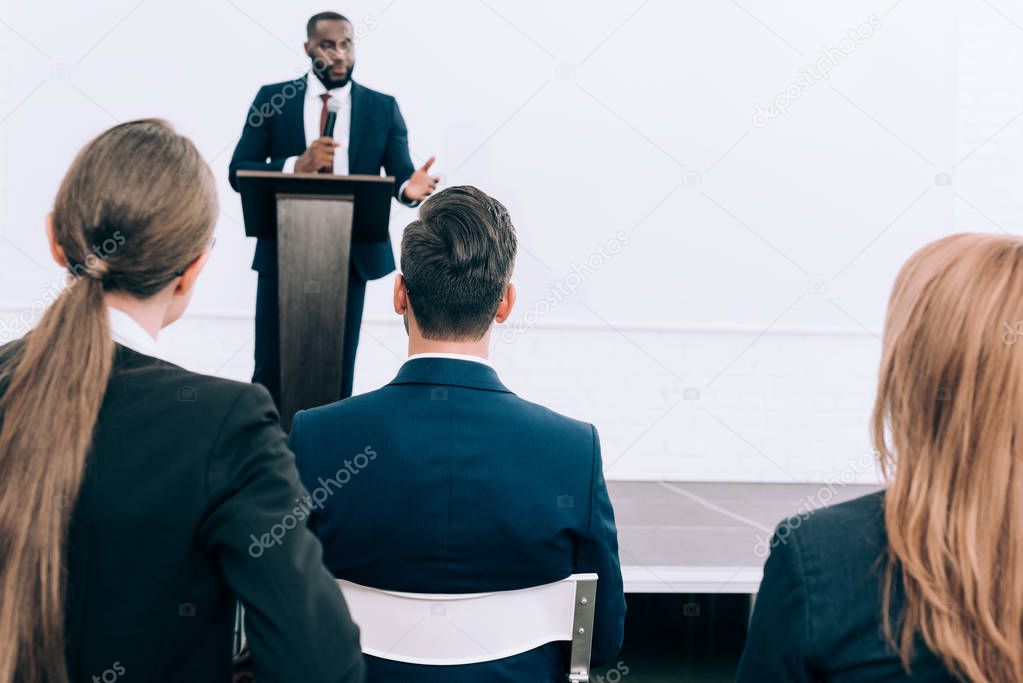 handsome african american speaker talking in front of audience conference hall