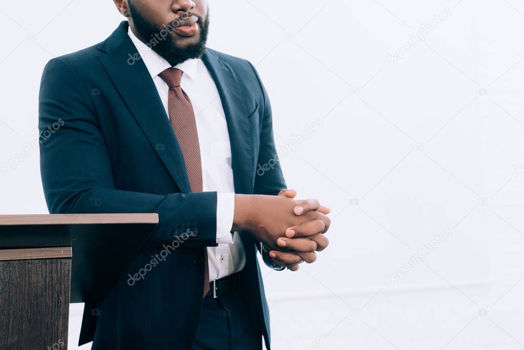 cropped image of african american businessman leaning on podium tribune during seminar in conference hall