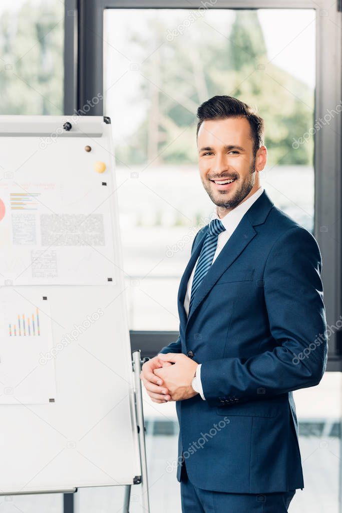 smiling lecturer standing at white board during presentation in conference hall