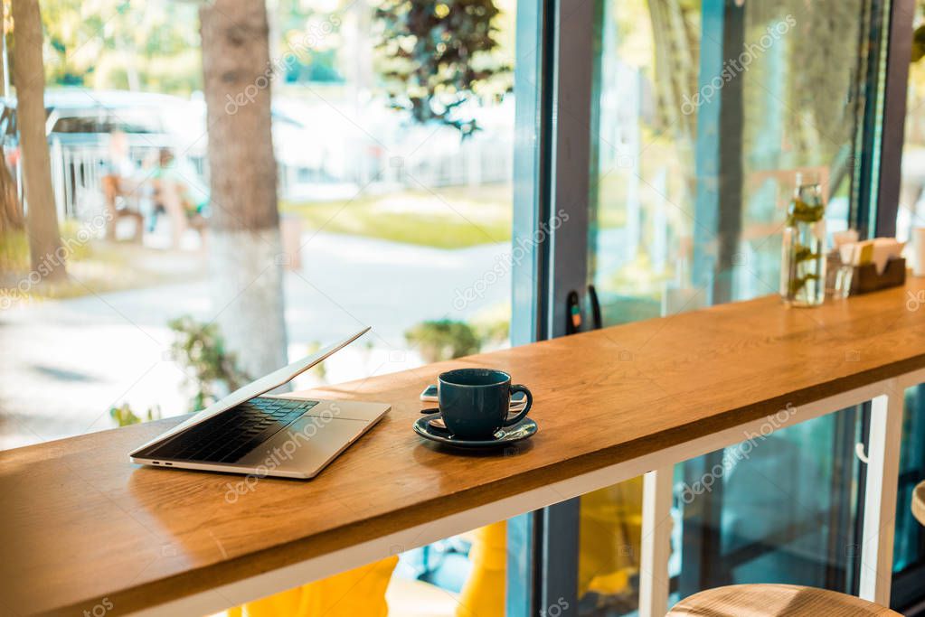 laptop and cup of coffee on wooden cafe counter