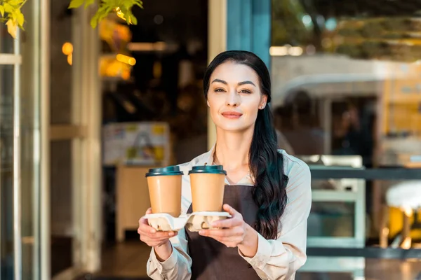 Gyönyörű Pincérnő Kötény Gazdaság Két Kávé Papírpohár Café Közelében — Stock Fotó