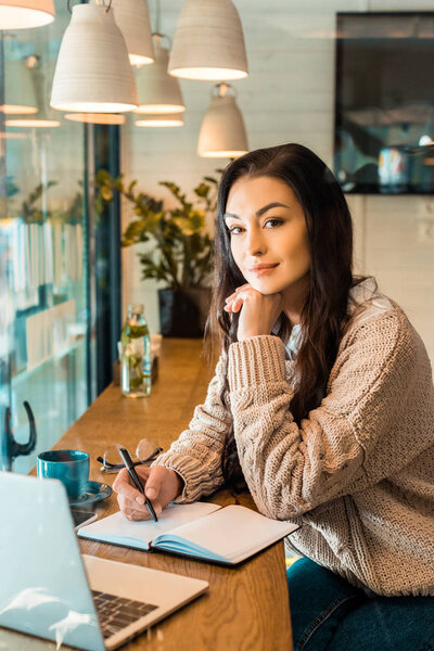 красивая фрилансер работает с планировщиком и ноутбуком в кафе
 