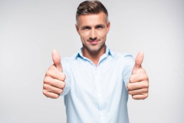 smiling adult man in shirt showing thumbs up and looking at camera isolated on white clipart