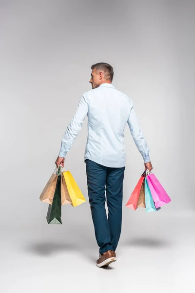 成年男子背着五颜六色的购物袋在白色的后方视图 — 图库照片