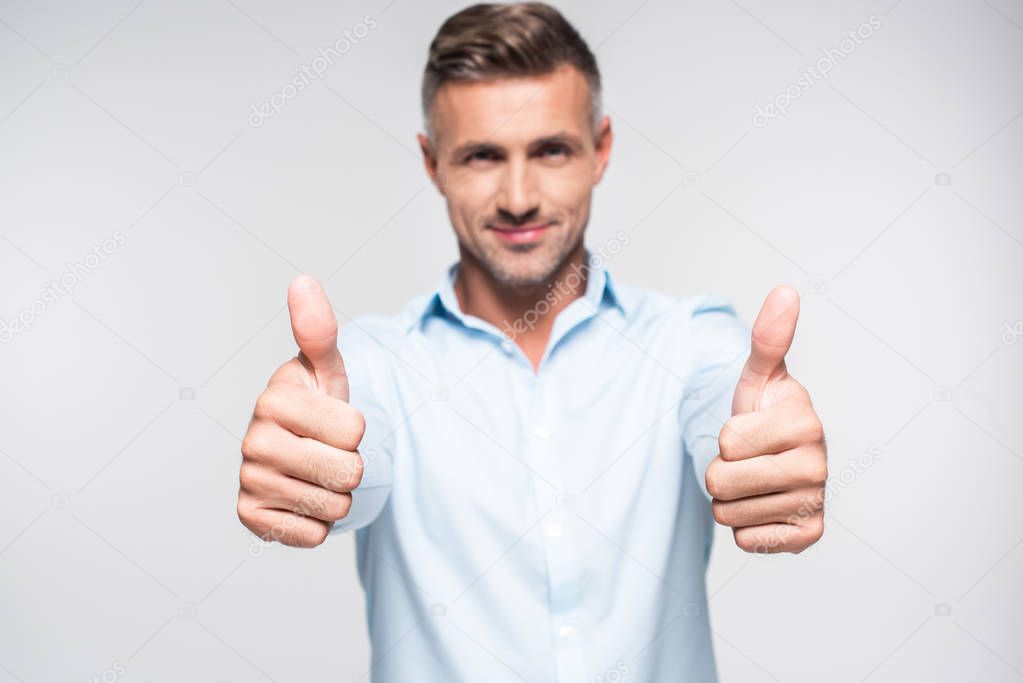 smiling adult man in shirt showing thumbs up and looking at camera isolated on white
