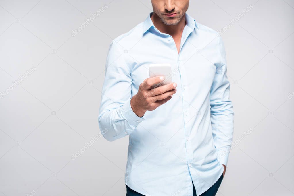 cropped shot of handsome adult man using smartphone isolated on white