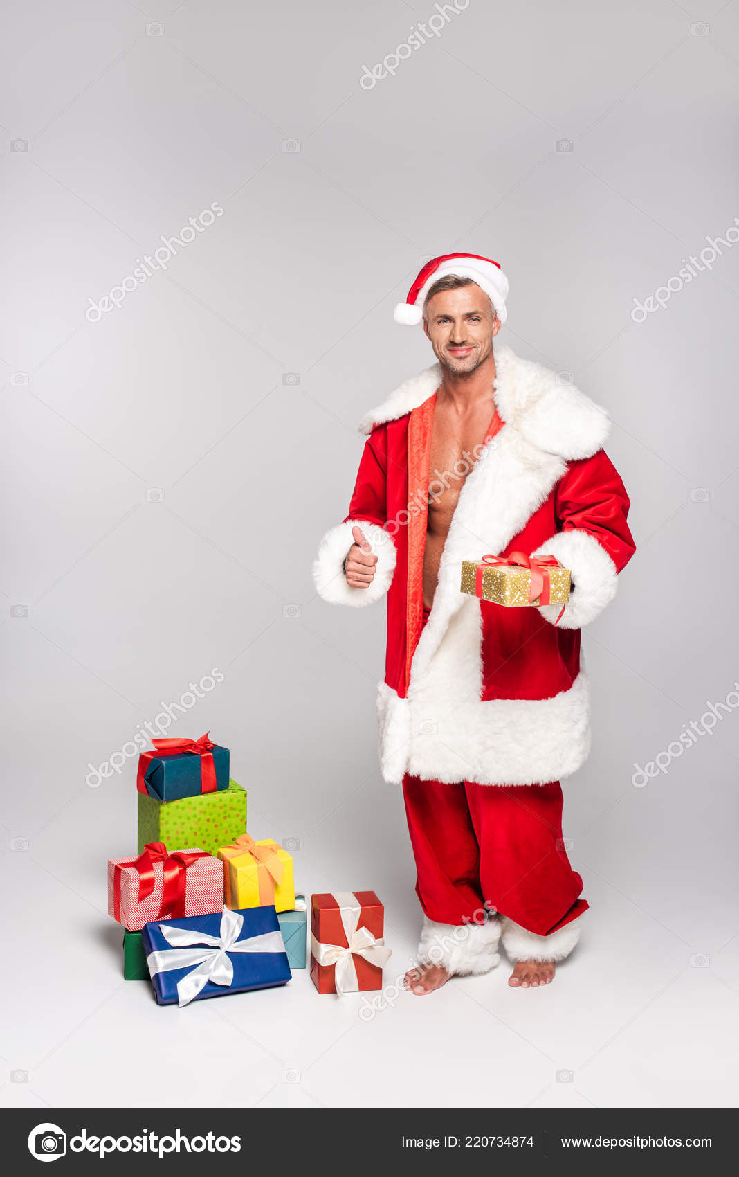Sexy Man Santa Costume Holding Christmas Present Showing Thumb