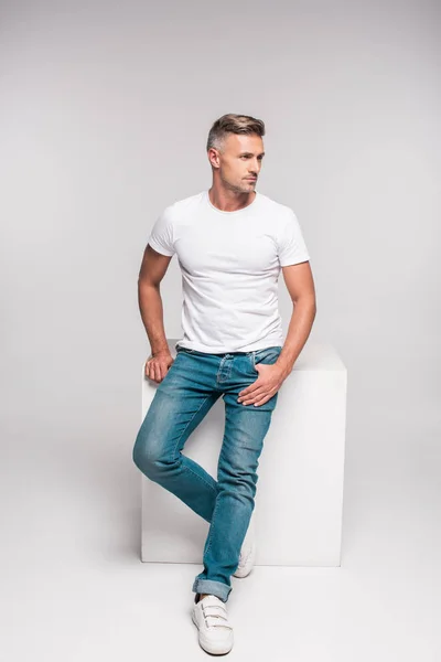 Schöner Mann Weißem Shirt Und Jeanshose Sitzt Und Wegschaut Auf — Stockfoto